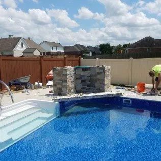 A man is working on a swimming pool in a backyard.