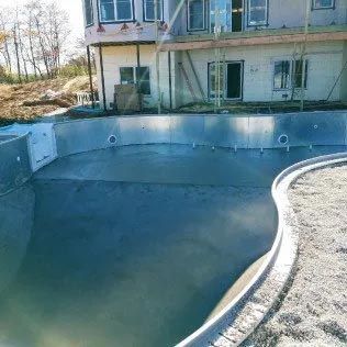 A large swimming pool is being built in front of a house.