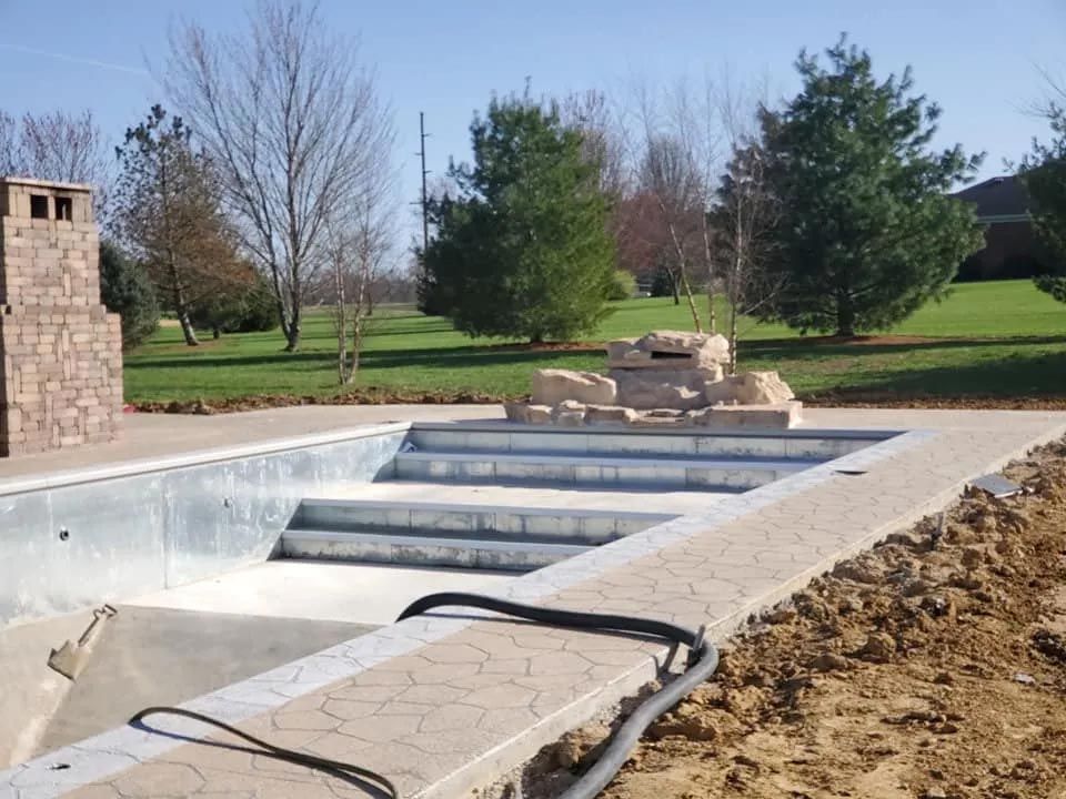 A swimming pool is being built with a fireplace in the background