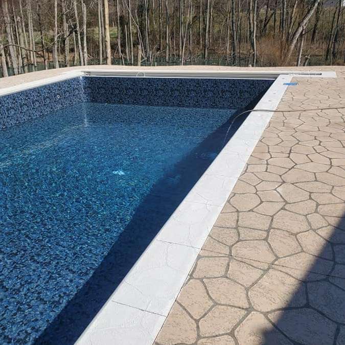 A large swimming pool surrounded by trees and a patio