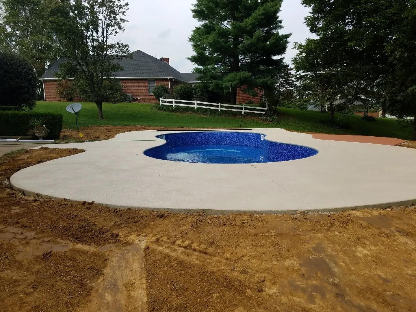 A swimming pool is being built in the backyard of a house