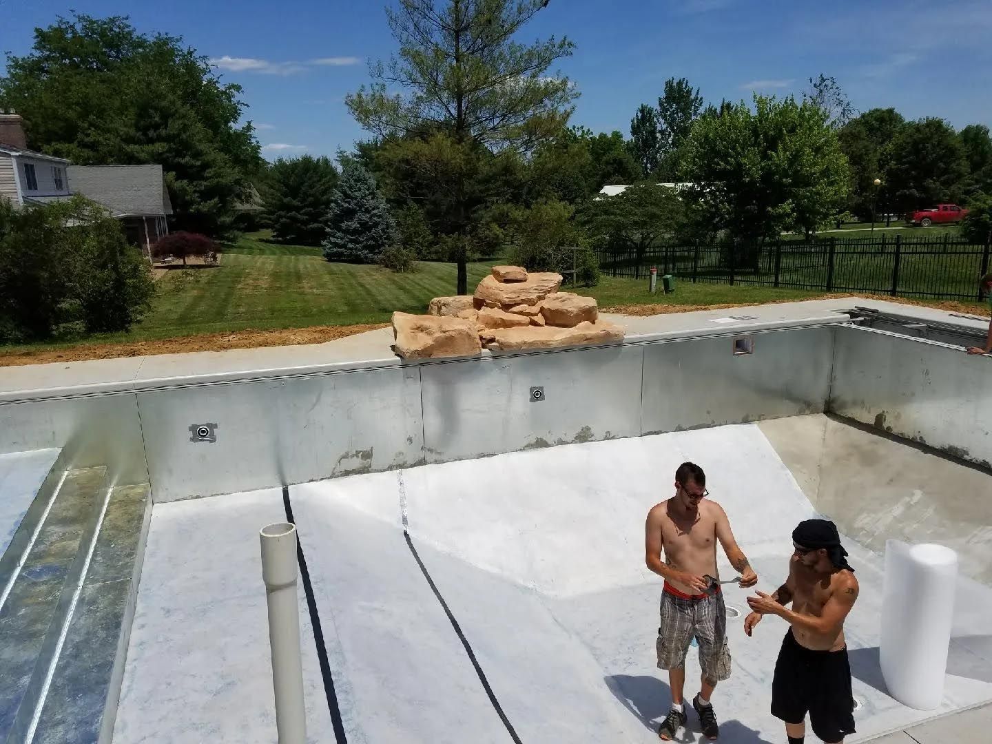 Two men are standing next to a swimming pool