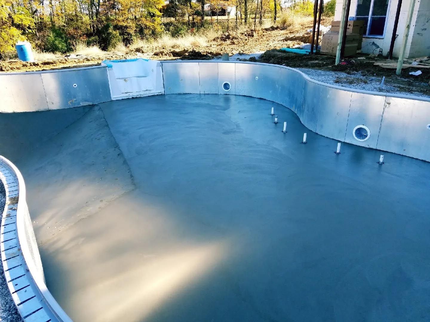 A swimming pool is being built in the backyard of a house.