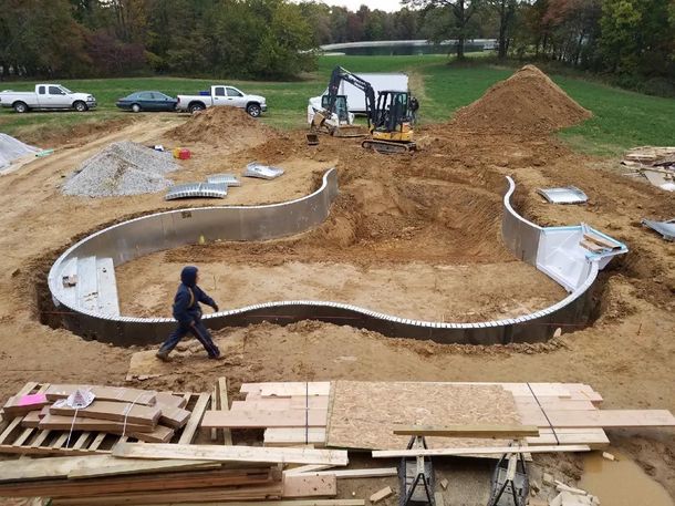 A man in a hooded jacket is walking through a construction site