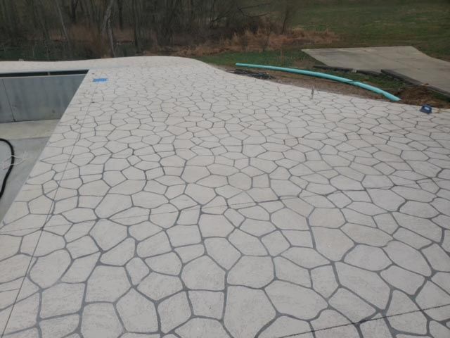 A patio with a pool in the background