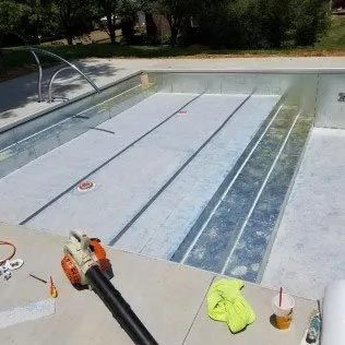 A swimming pool is being remodeled and a blower is sitting next to it.