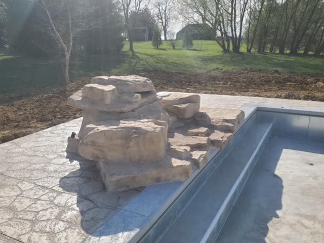 A large rock is sitting next to a swimming pool