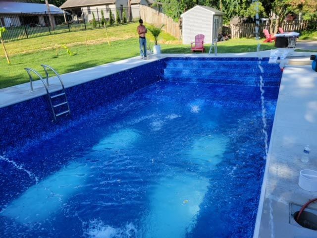 A man is standing on the edge of a swimming pool.