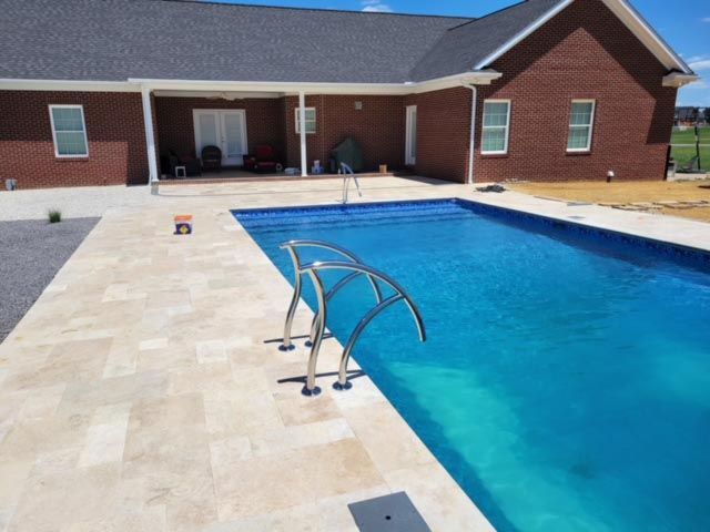 A large swimming pool in front of a brick house