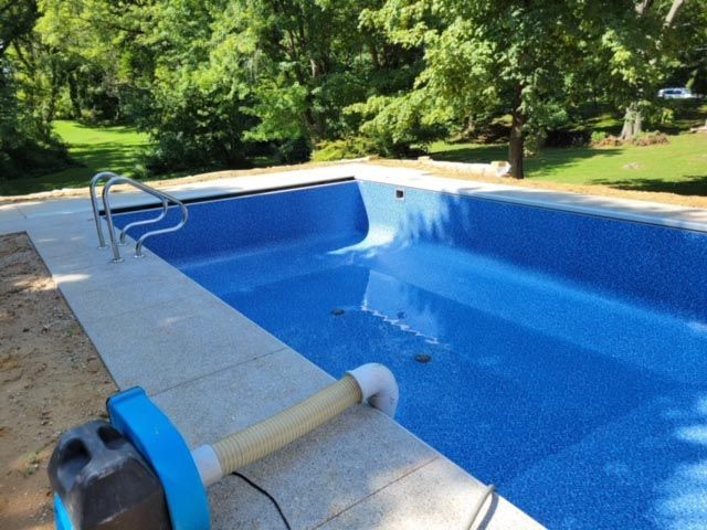 A blue swimming pool with a vacuum on the side of it