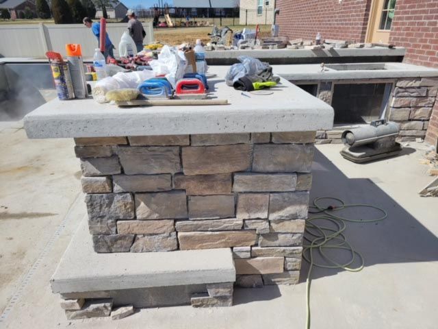 A stone pillar with a concrete top is sitting on a concrete surface.
