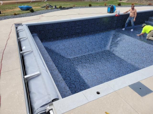 Two men are working on a large swimming pool