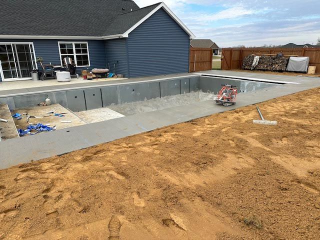 A swimming pool is being built in the backyard of a house.