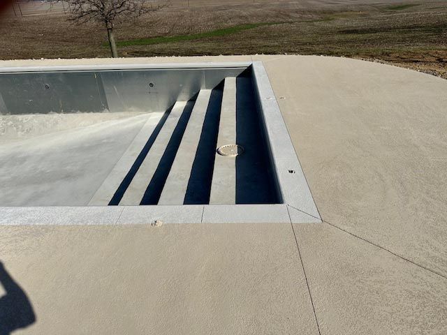 A swimming pool with a concrete deck and stairs
