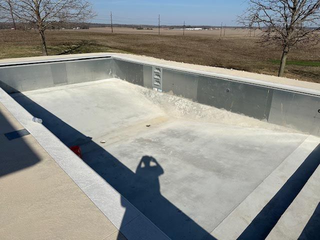 An empty swimming pool with a field in the background