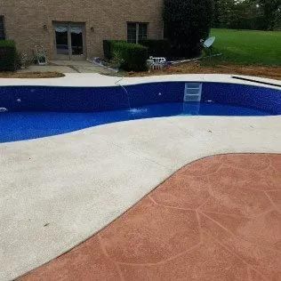 A large swimming pool with a ladder in it is sitting in front of a house.
