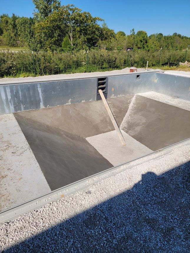 A swimming pool is being built with concrete and a shovel.