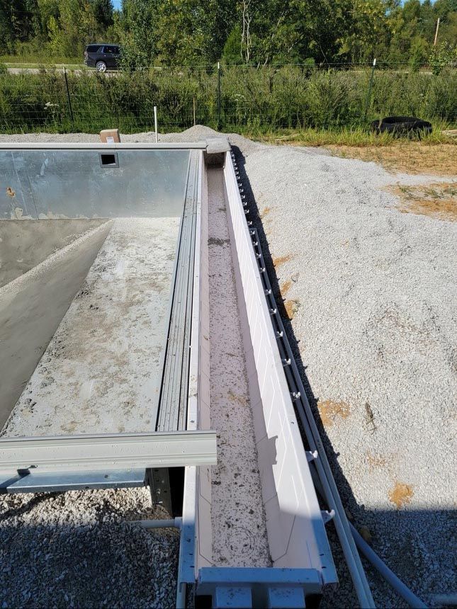 A swimming pool is being built in a dirt field.