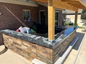 A man is laying on a stone wall on a patio.