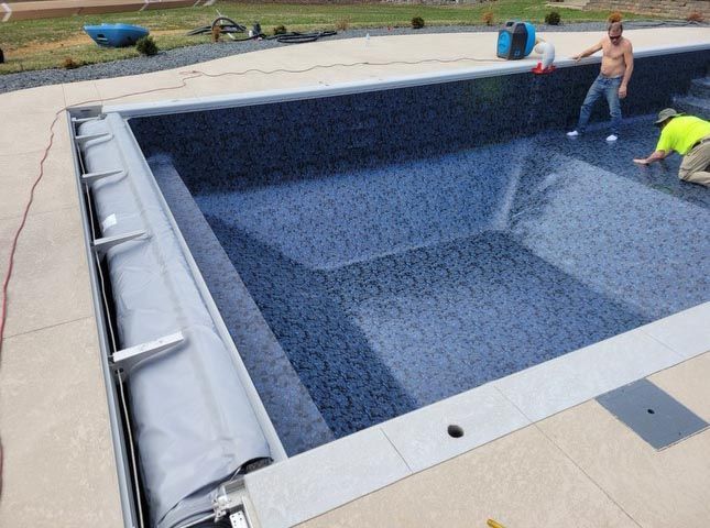 Two men are working on a large swimming pool.