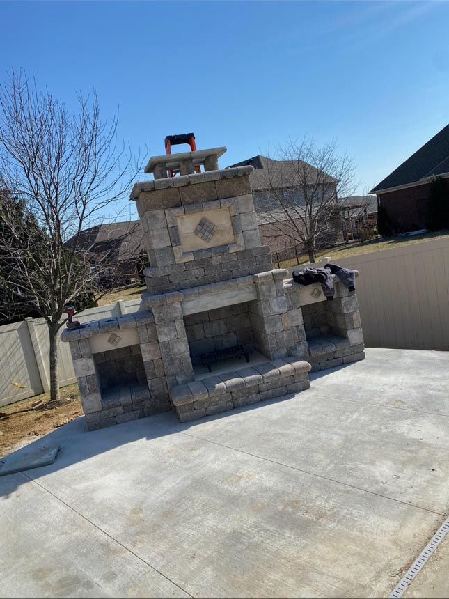 A large stone fireplace is sitting on top of a concrete patio.