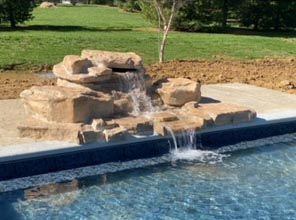 There is a waterfall in the middle of a swimming pool.