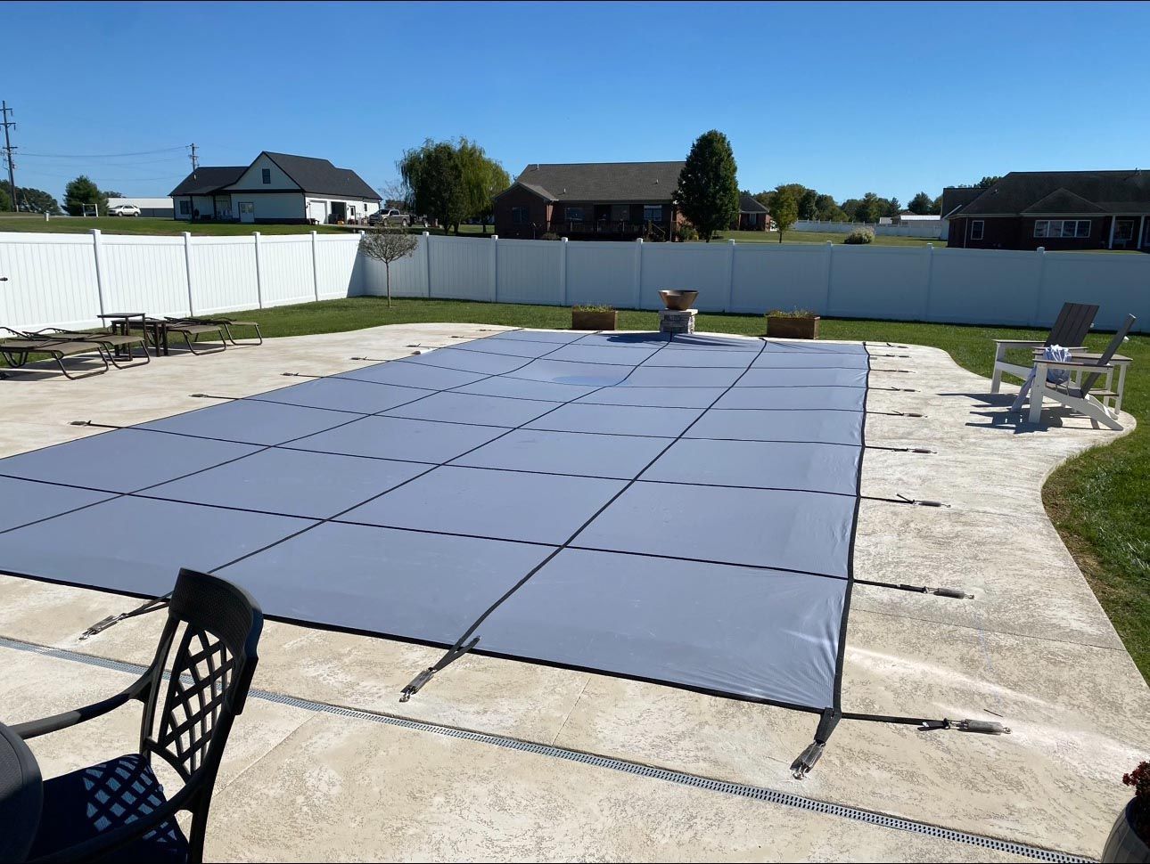 A large swimming pool is covered with a gray cover.