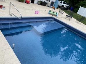 A large swimming pool with stairs and a white truck parked in the background.