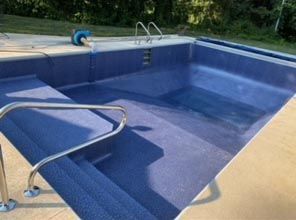 A blue swimming pool with stairs leading to it.