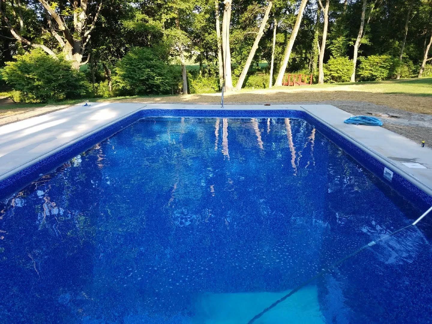 A large blue swimming pool with trees in the background