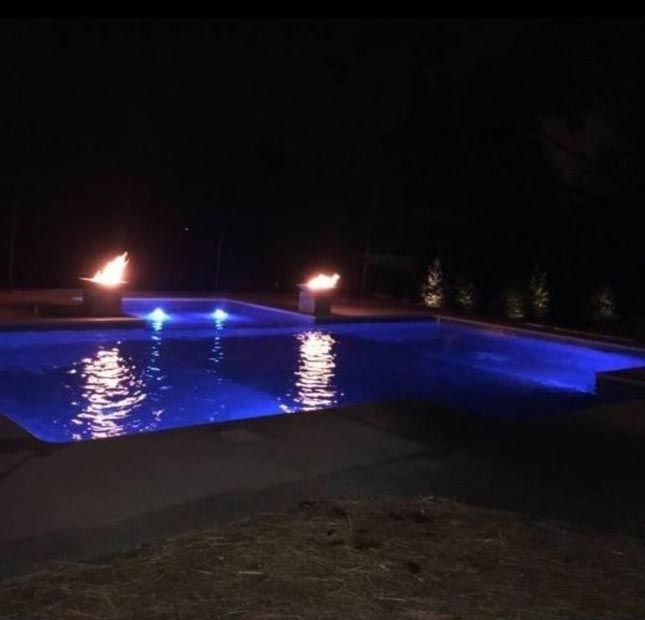 A swimming pool is lit up at night with blue lights