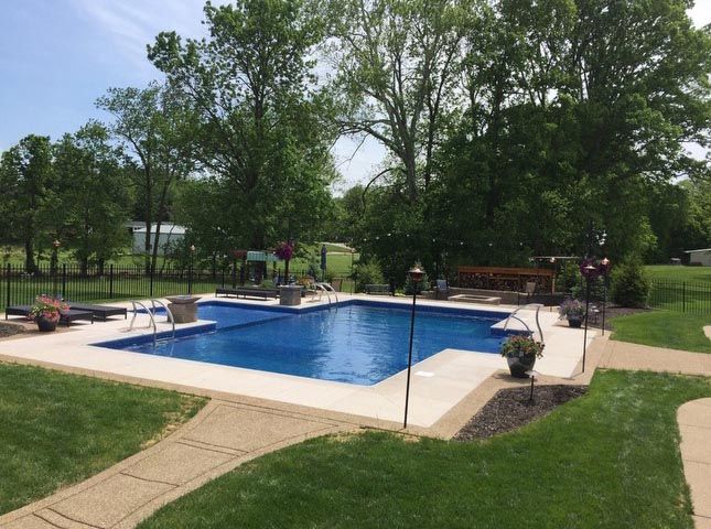 A large swimming pool in the middle of a lush green field