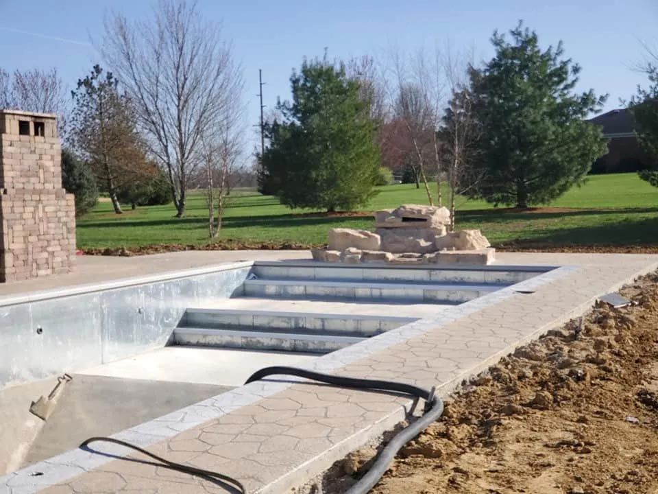 An empty swimming pool with a fireplace in the background