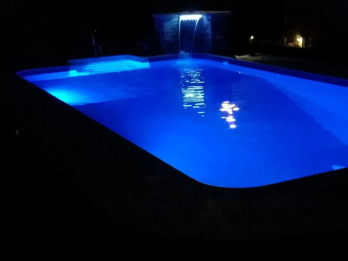 A swimming pool is lit up at night with blue lights
