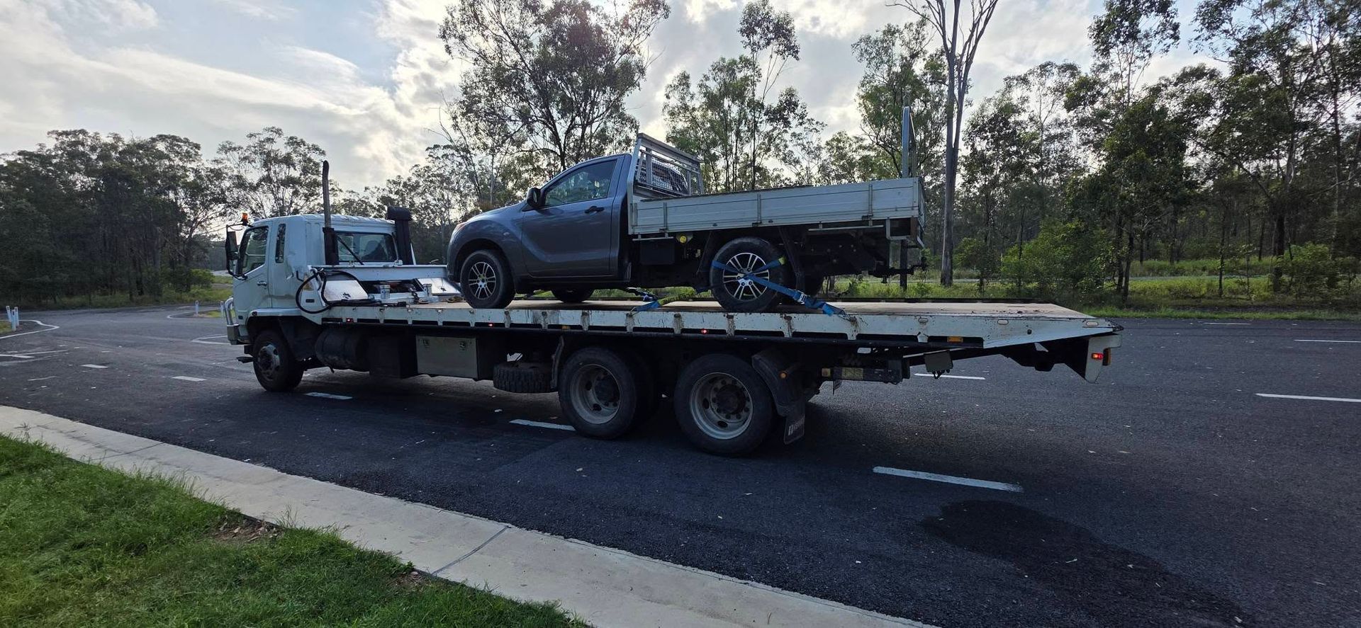 Tow Truck Carrying a Pickup Truck on a Road Near Trees — Agnes Water Transport and Towing in Agnes Water, QLD