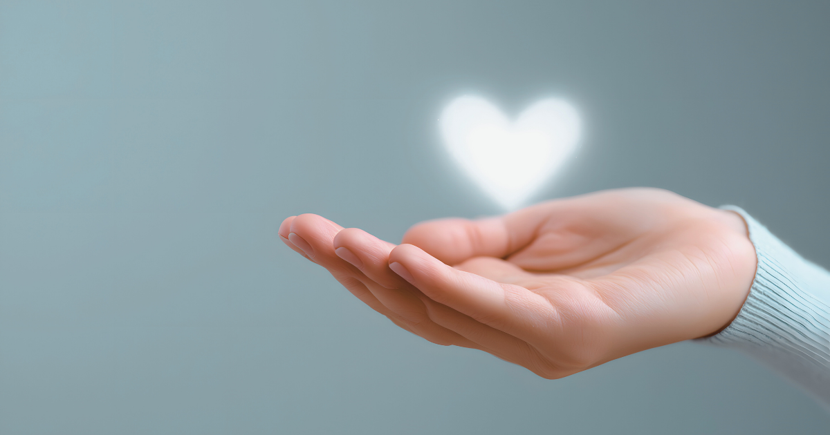 A photo of a woman's hand cupping a small, glowing heart illustration