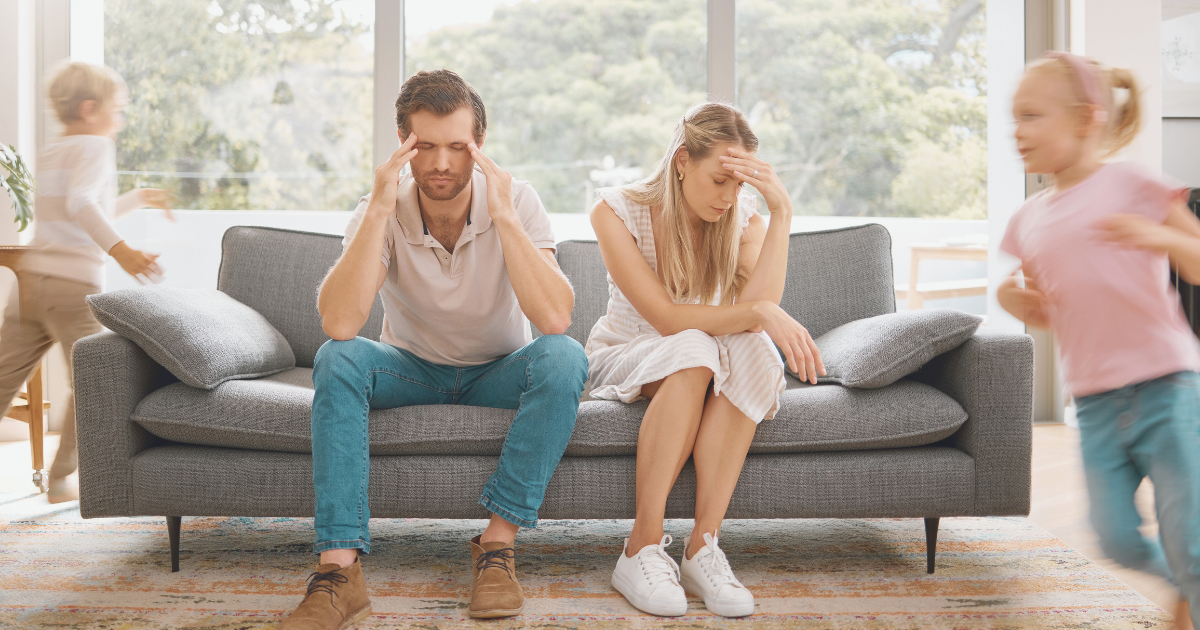 A young caucasian couple overwhelmed and overstimulated by children running in circles