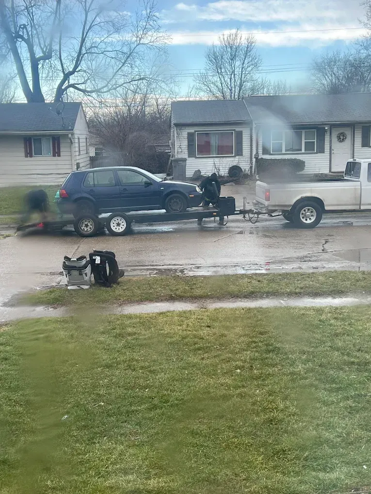 A car is being towed by a truck on a trailer.