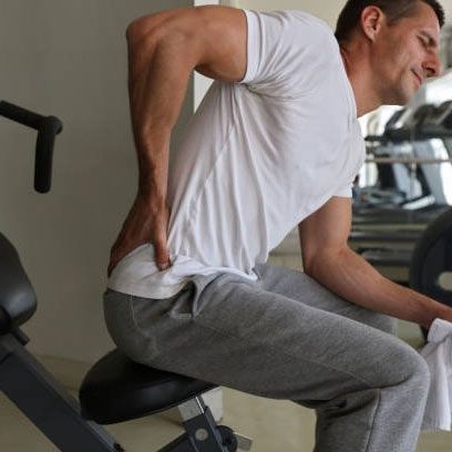 A man is sitting on a bike holding his back in pain