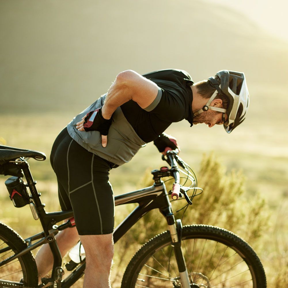 A man wearing a helmet is leaning on a bicycle