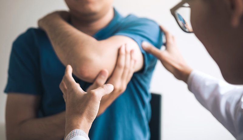A man is getting his elbow examined by a doctor.