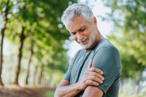 An older man is holding his shoulder in pain.