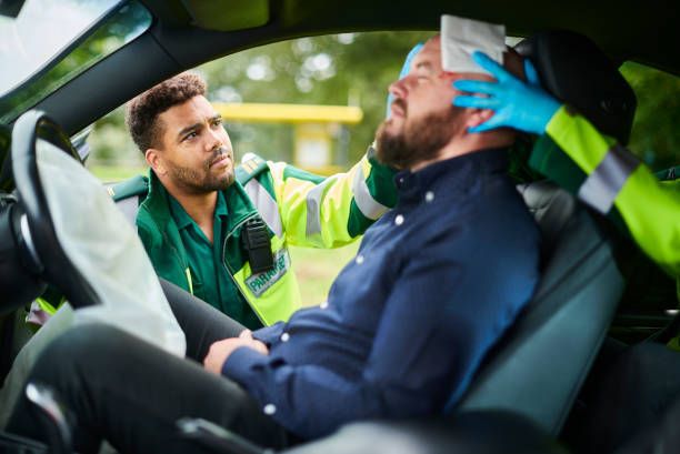 A man is sitting in a car with a bandage on his head.