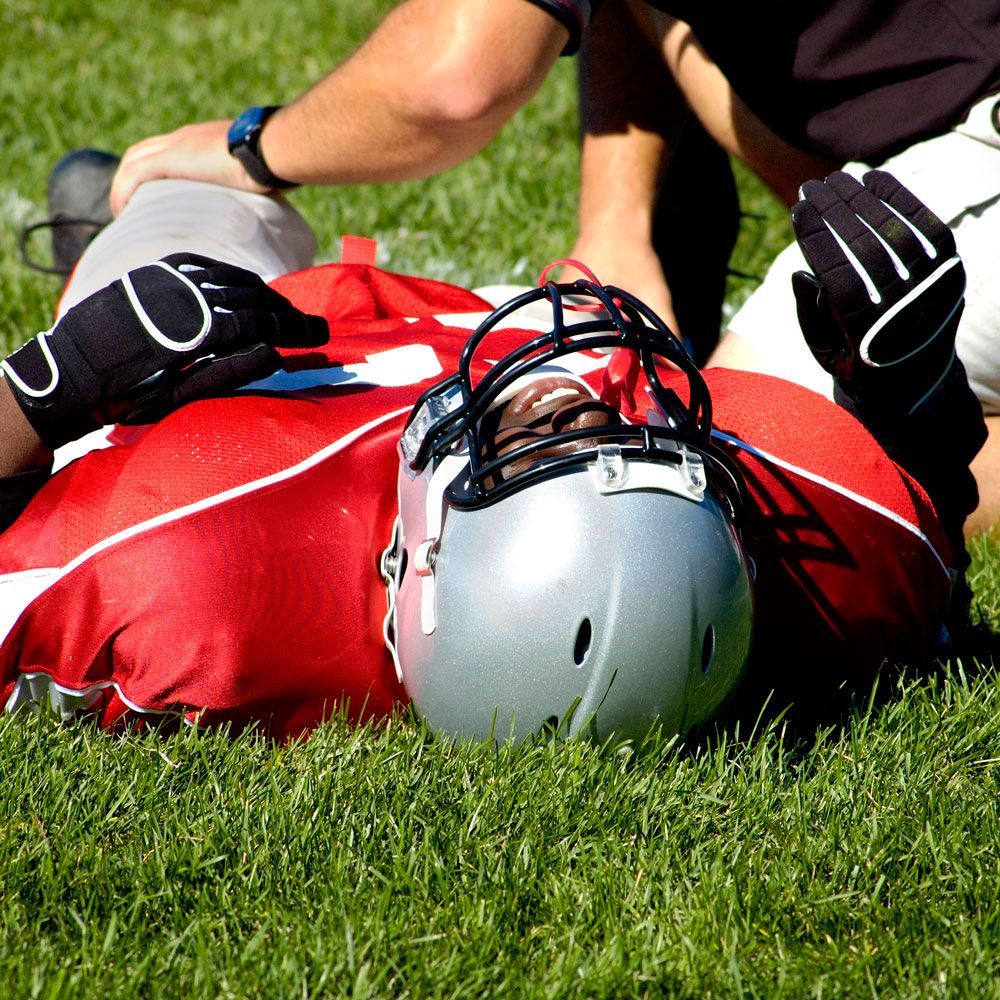 A football player is laying on the grass with a helmet on