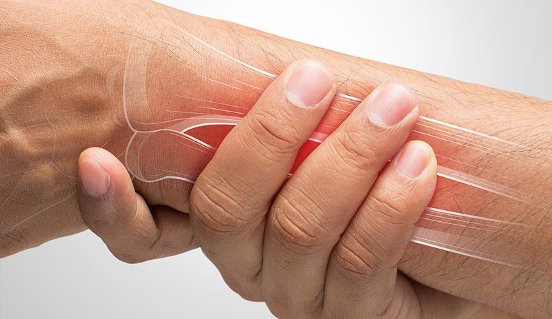 A person is holding their wrist in pain.
