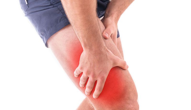 A man is holding his leg in pain.