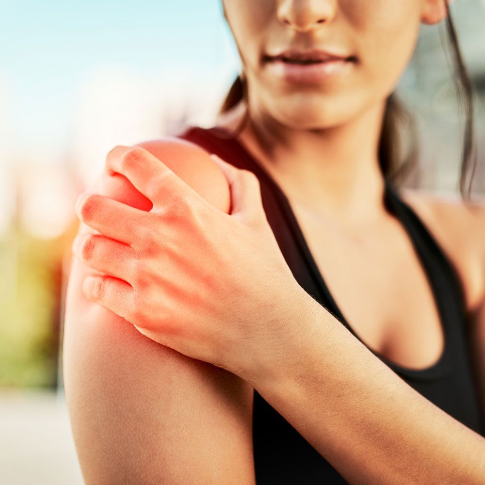 A woman is holding her shoulder in pain.
