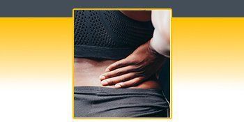 A person is holding their back in pain. A person is holding their back in pain.
