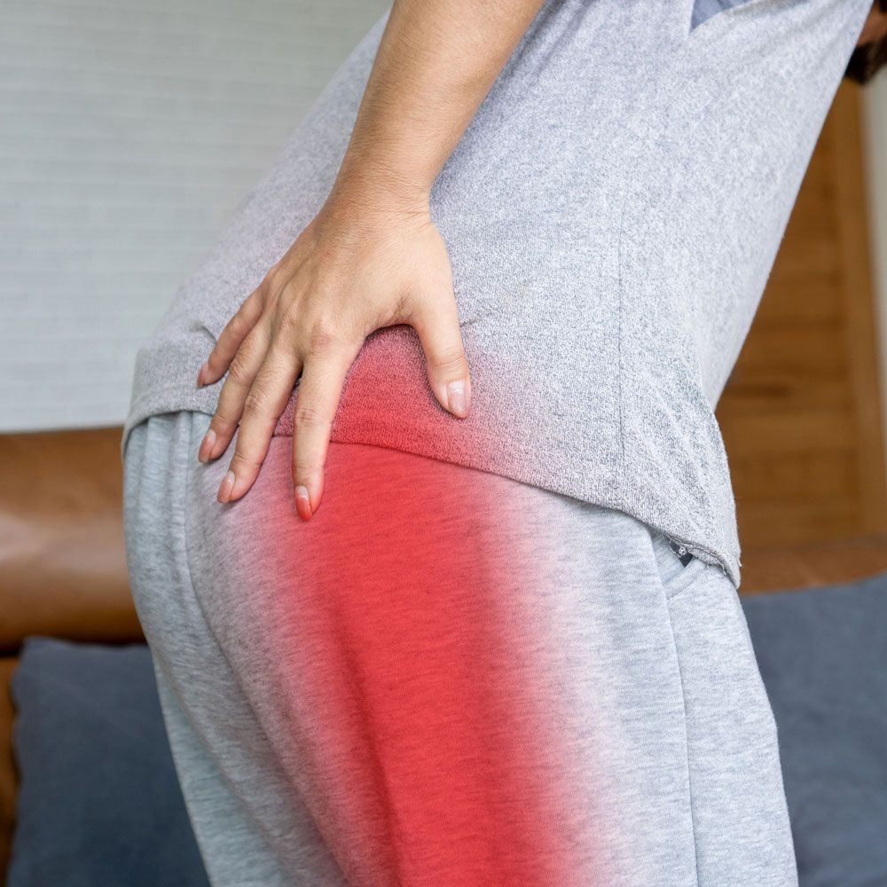 A woman is holding her hip in pain.