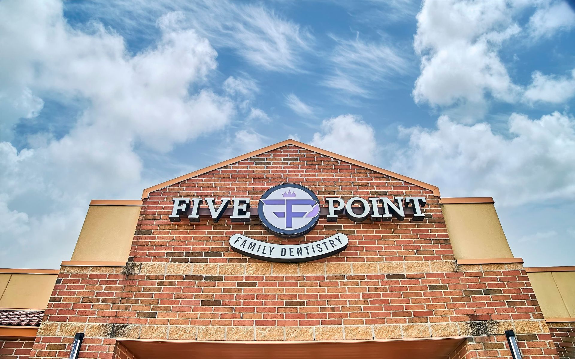 Five Point Family Dentistry building with red brick exterior, under a blue sky with clouds.